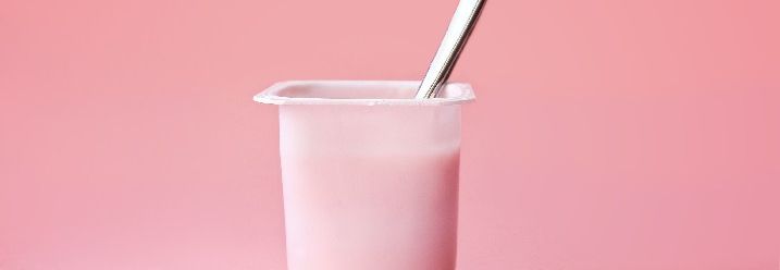 Joghurtbecher vor rosafarbenen Hintergrund